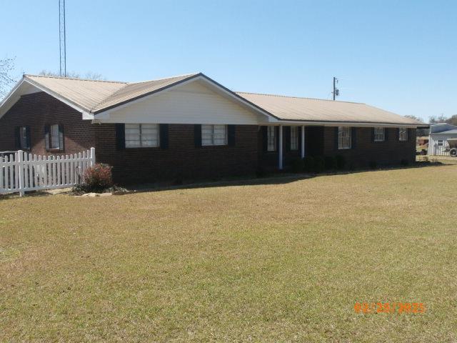 ranch-style home featuring fence and a front lawn