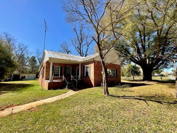 view of front of home featuring brick siding, covered porch, and a front yard