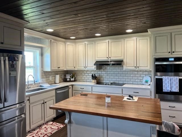 1104 Old Thomasville Rd, Cairo, GA 39828 - kitchen with butcher block countertops, appliances with stainless steel finishes, wooden ceiling, decorative backsplash, and under cabinet range hood