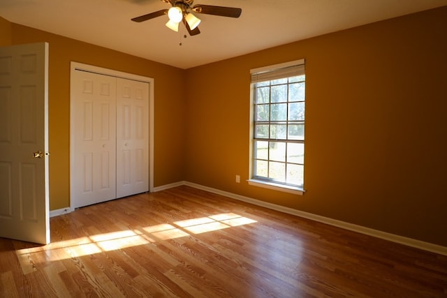 unfurnished bedroom featuring a closet, ceiling fan, baseboards, and wood finished floors