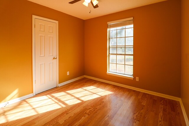 spare room with a healthy amount of sunlight, ceiling fan, baseboards, and wood finished floors