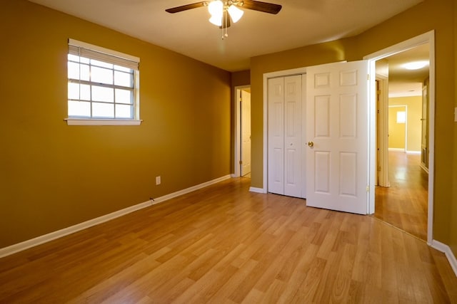 unfurnished bedroom featuring a closet, light wood-style flooring, a ceiling fan, and baseboards