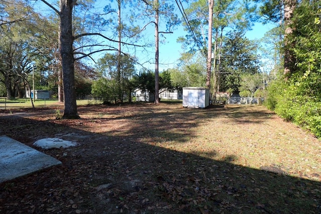 view of yard featuring an outbuilding, a shed, and fence