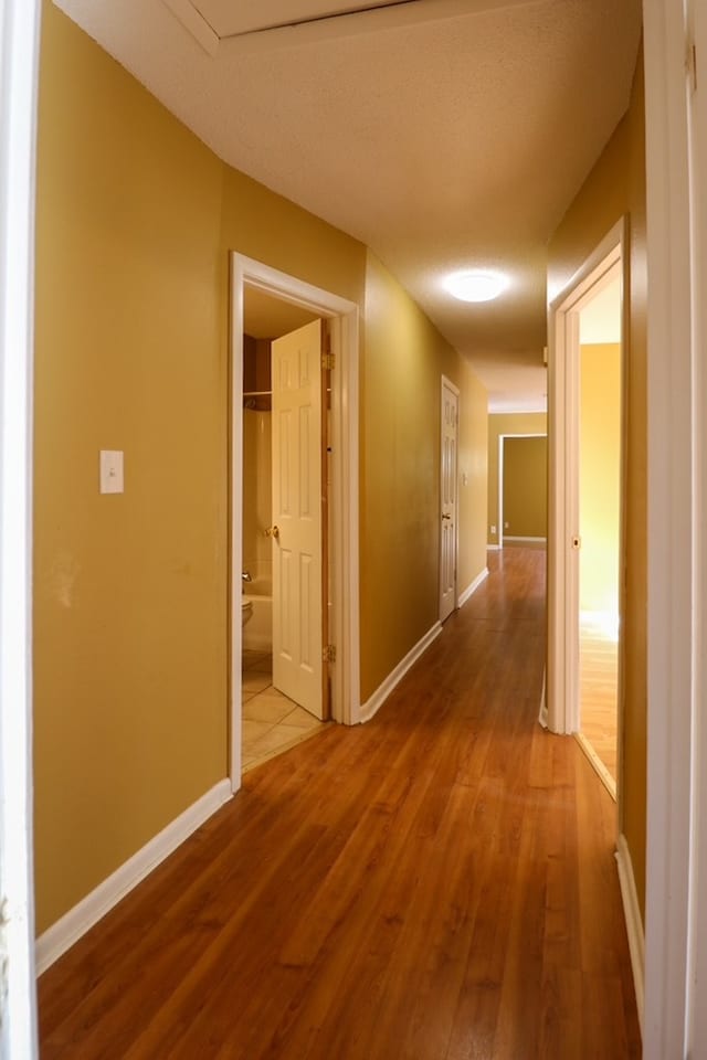 corridor featuring baseboards and wood finished floors