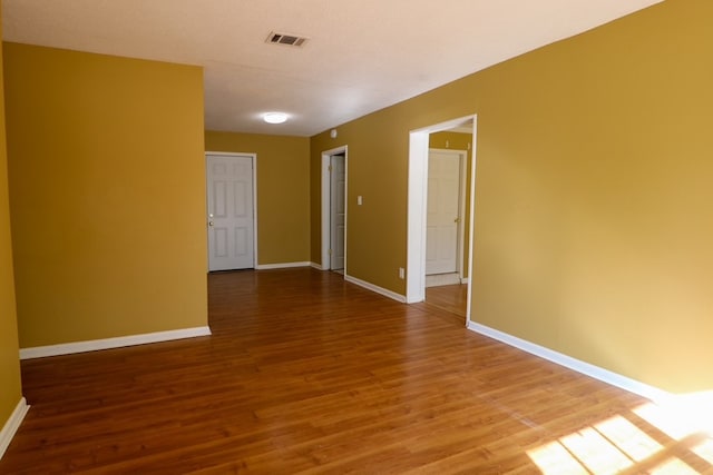 spare room featuring visible vents, baseboards, and wood finished floors