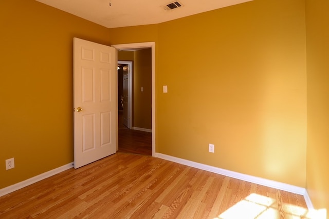 unfurnished room with light wood-type flooring, visible vents, and baseboards