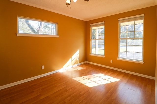 empty room featuring ceiling fan, baseboards, wood finished floors, and ornamental molding