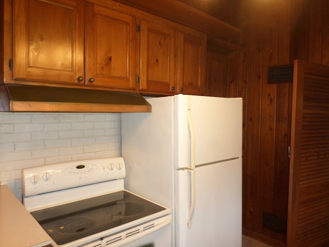 701 Collier St, Bainbridge, GA 39819 - kitchen featuring white appliances, under cabinet range hood, brown cabinetry, wood walls, and light countertops