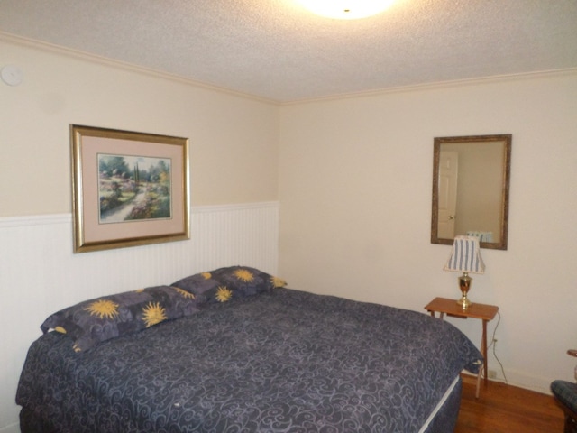 701 Collier St, Bainbridge, GA 39819 - bedroom with a wainscoted wall, a textured ceiling, crown molding, and dark wood finished floors