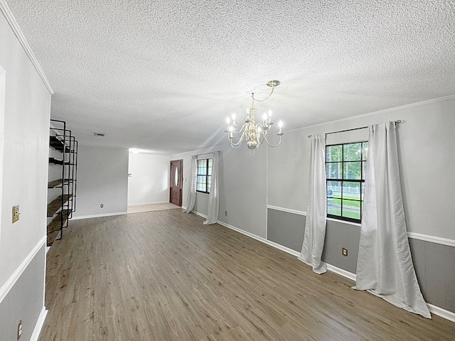 empty room featuring hardwood / wood-style flooring, a notable chandelier, and a textured ceiling