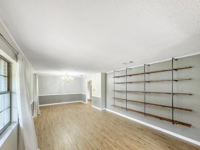 interior space with a chandelier, a textured ceiling, and light hardwood / wood-style flooring