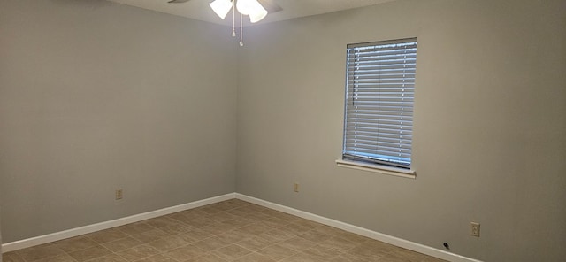 spare room with a ceiling fan and baseboards