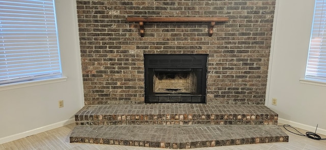 room details with a brick fireplace, baseboards, and wood finished floors