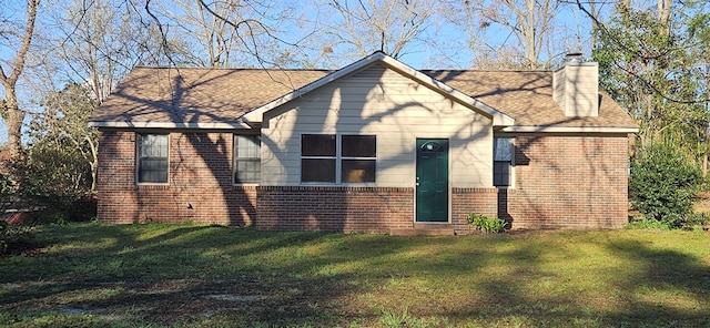 view of front of house with brick siding, a chimney, a front lawn, and a shingled roof