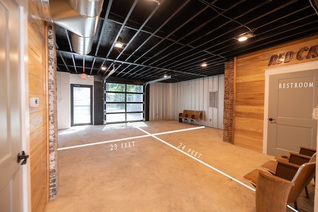 miscellaneous room featuring wooden walls, electric panel, and concrete floors