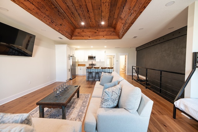 living room featuring a tray ceiling, light hardwood / wood-style floors, and wood ceiling