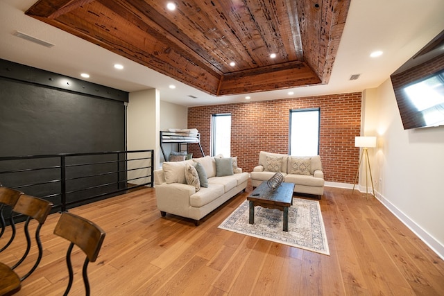 living room with a raised ceiling, wooden ceiling, brick wall, and light hardwood / wood-style flooring