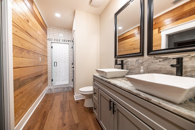 bathroom featuring hardwood / wood-style floors, vanity, wood walls, toilet, and an enclosed shower