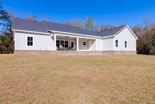 rear view of property featuring a lawn, board and batten siding, a ceiling fan, and a patio area