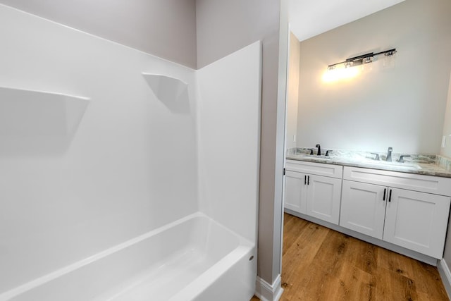 bathroom with a sink, a tub, walk in shower, and wood finished floors