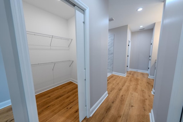 corridor with light wood-style floors, recessed lighting, and baseboards