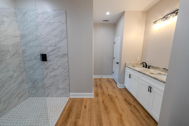 bathroom featuring visible vents, a sink, wood finished floors, baseboards, and walk in shower