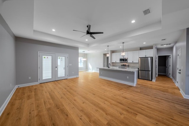 kitchen featuring stainless steel appliances, a raised ceiling, visible vents, and white cabinets