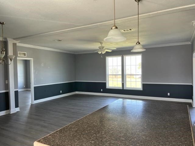 spare room featuring dark wood-style flooring, visible vents, ornamental molding, a ceiling fan, and baseboards