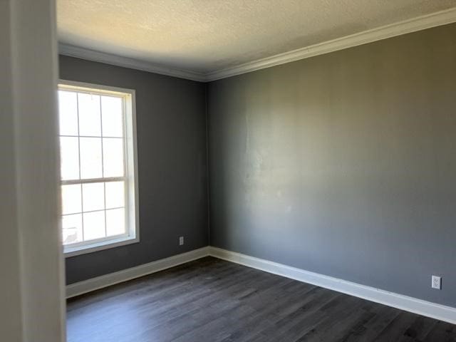 spare room featuring dark wood-style floors, plenty of natural light, baseboards, and crown molding