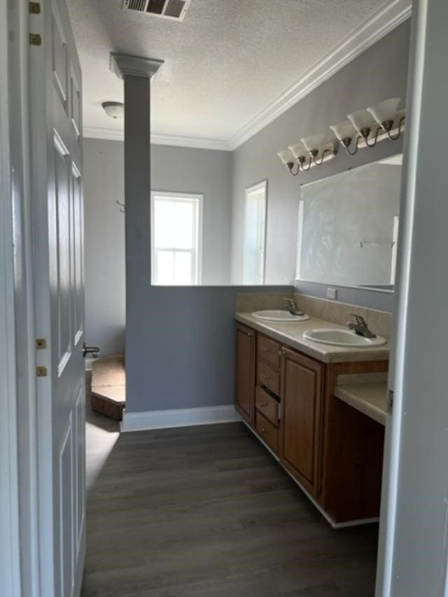 full bath featuring ornamental molding, a sink, a textured ceiling, and wood finished floors