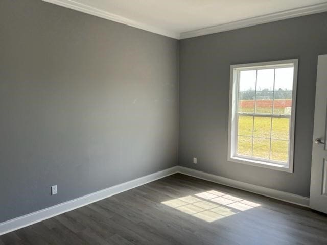 empty room with a healthy amount of sunlight, baseboards, dark wood finished floors, and crown molding