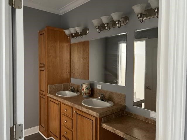 bathroom with double vanity, crown molding, baseboards, and a sink