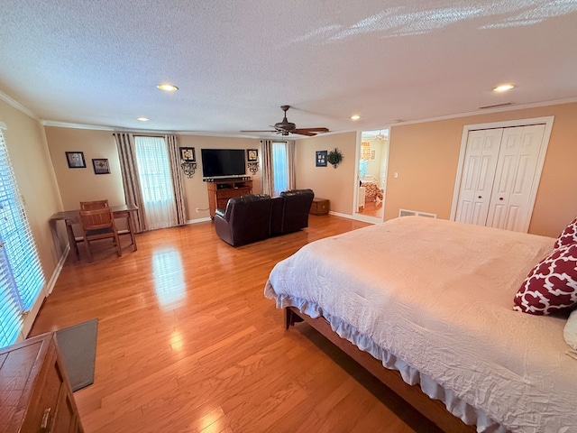 bedroom with crown molding, light wood-style flooring, visible vents, and a textured ceiling