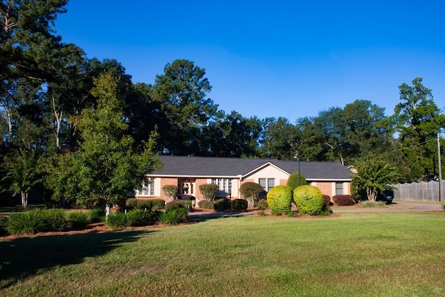 ranch-style home with a front lawn and fence