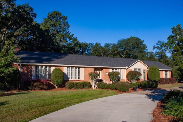 ranch-style home with a front yard, brick siding, and driveway