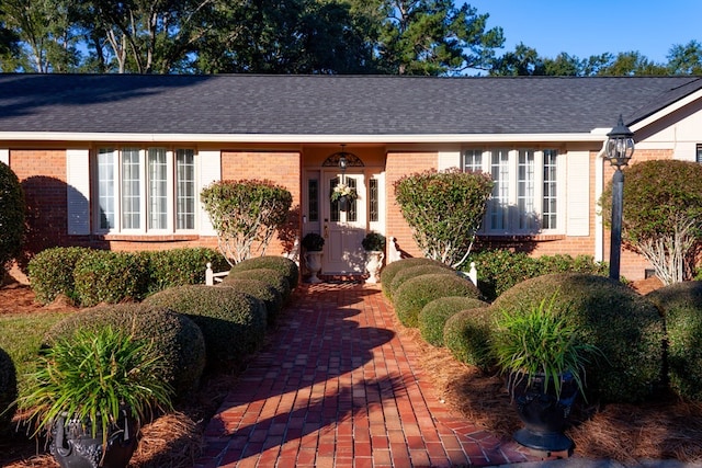 single story home featuring brick siding and a shingled roof