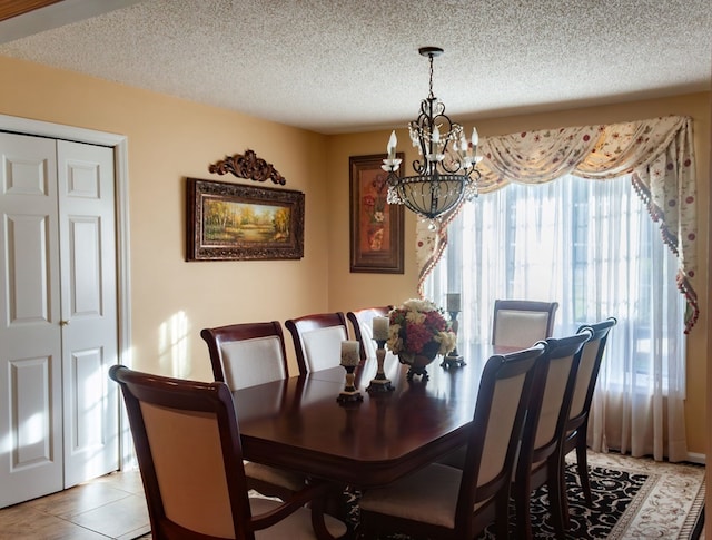 dining room with a notable chandelier, light tile patterned floors, and a textured ceiling