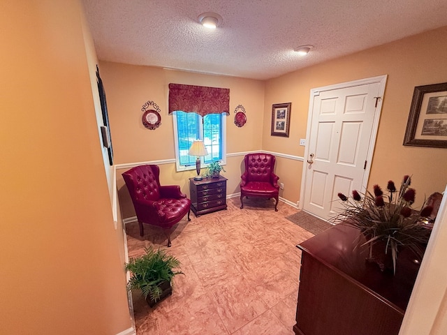 living area featuring a textured ceiling and baseboards