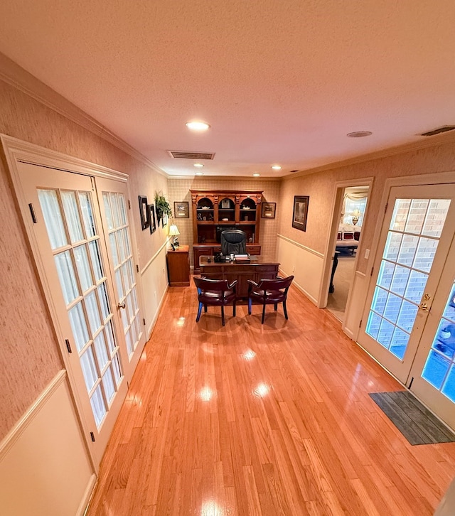 dining room featuring visible vents, ornamental molding, light wood-style flooring, french doors, and a textured ceiling