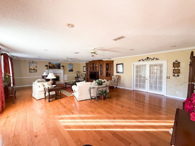 living area with a fireplace, crown molding, ceiling fan, and wood finished floors