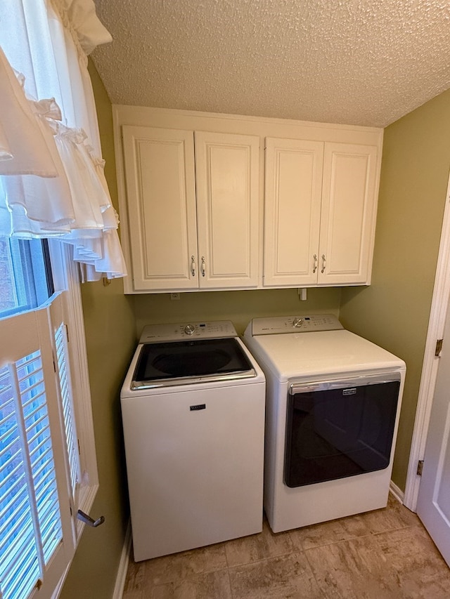 laundry area with washer and dryer, baseboards, cabinet space, and a textured ceiling