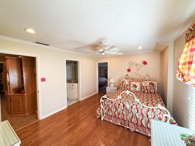 bedroom with visible vents, baseboards, ornamental molding, wood finished floors, and a textured ceiling