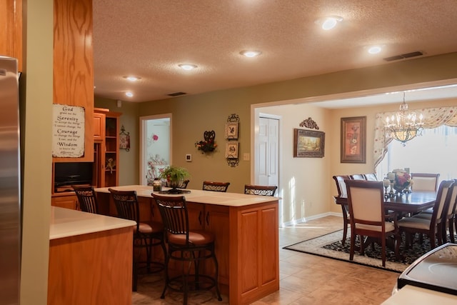 kitchen with a kitchen bar, visible vents, a center island, and light countertops