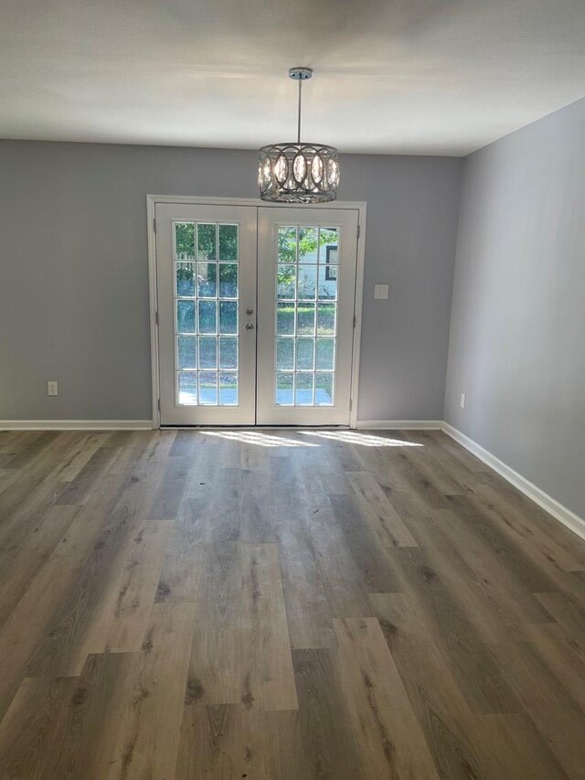 spare room featuring a chandelier, french doors, baseboards, and wood finished floors