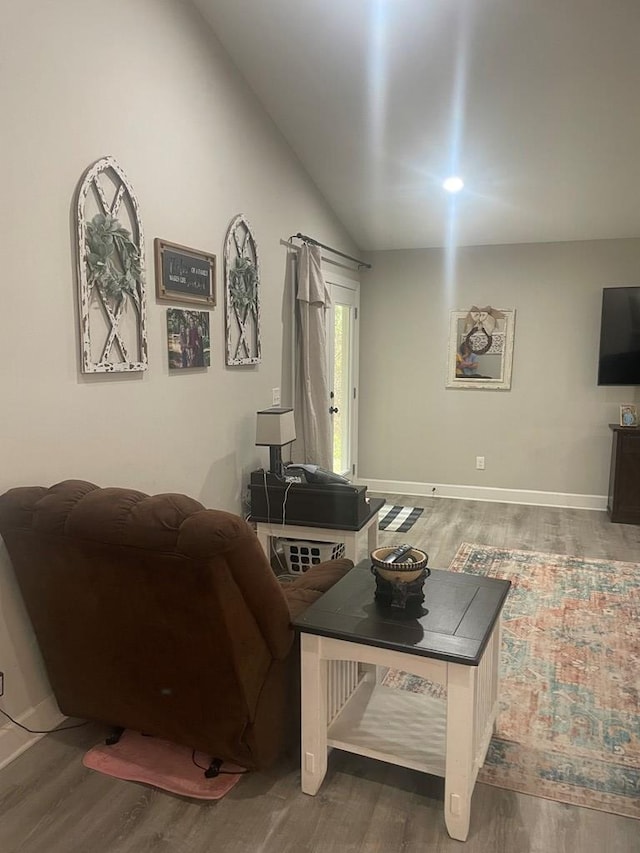 living area featuring baseboards, wood finished floors, and vaulted ceiling