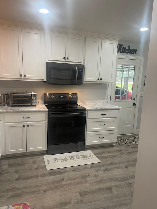 kitchen featuring wood finished floors, black appliances, white cabinets, and a toaster