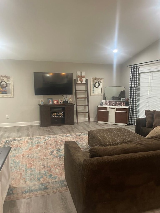 living area with baseboards, wood finished floors, and vaulted ceiling