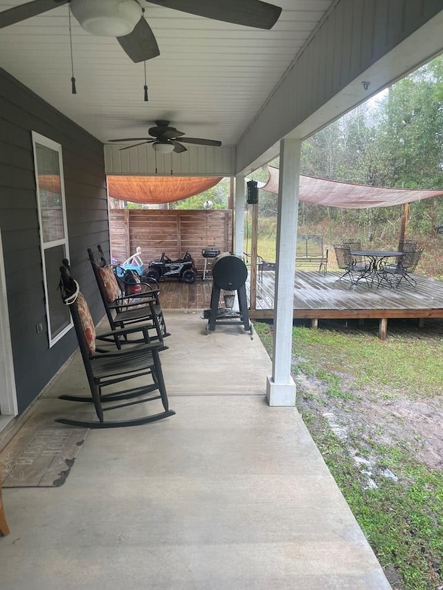 view of patio / terrace featuring a wooden deck, outdoor dining space, a ceiling fan, and fence