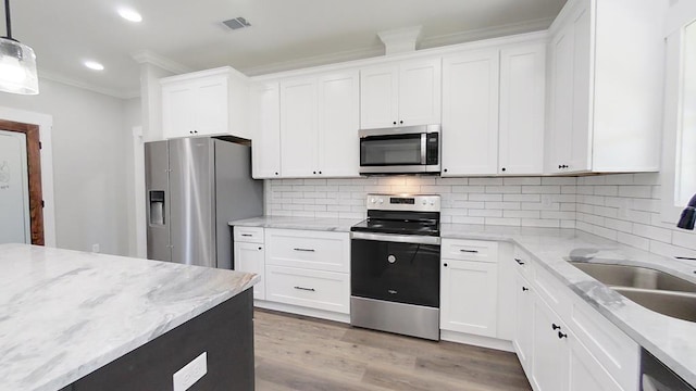 kitchen featuring stainless steel appliances, decorative light fixtures, and white cabinets