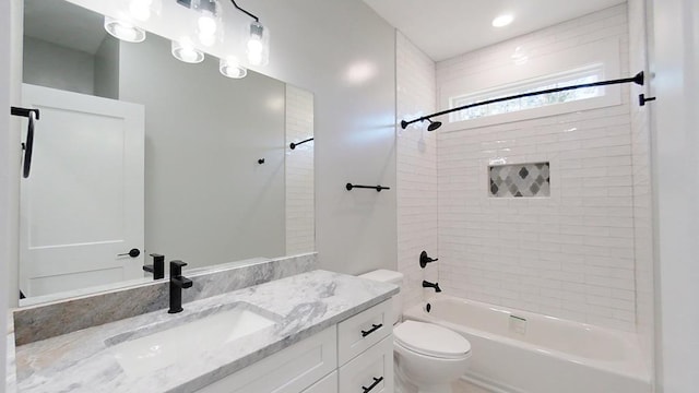 full bathroom featuring tiled shower / bath combo, vanity, and toilet